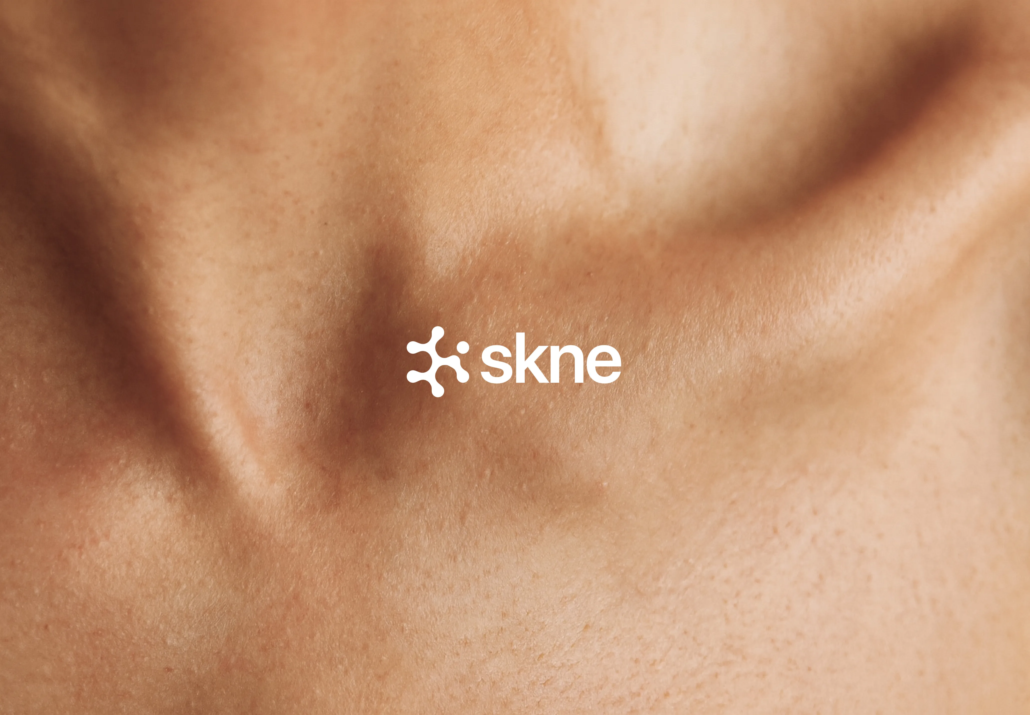 Close-up of smooth skin with the white skne logo overlayed in the center.